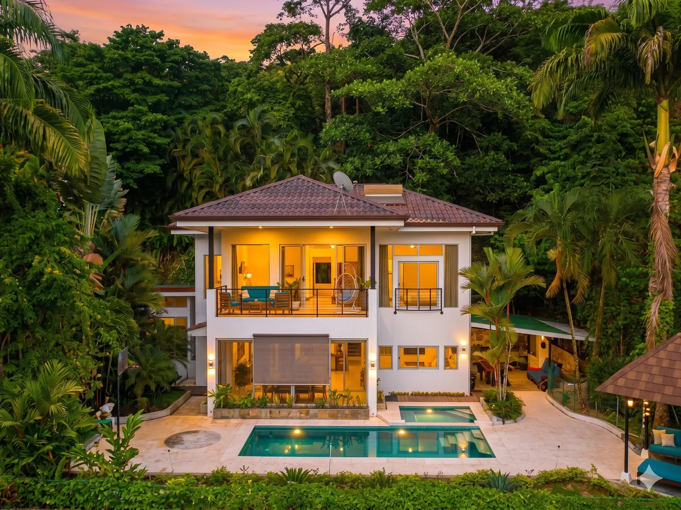Casa de lujo construida por Kosago Corp en Costa Rica, con piscina y terrazas iluminadas al atardecer